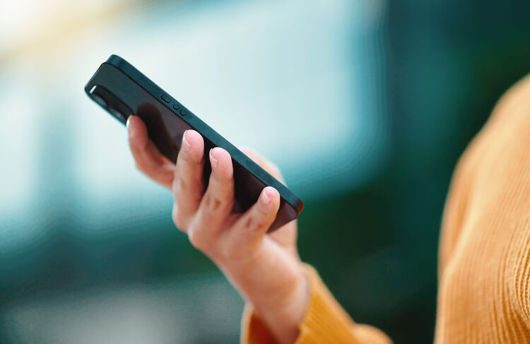 Close-up of a hand holding a smartphone outdoors